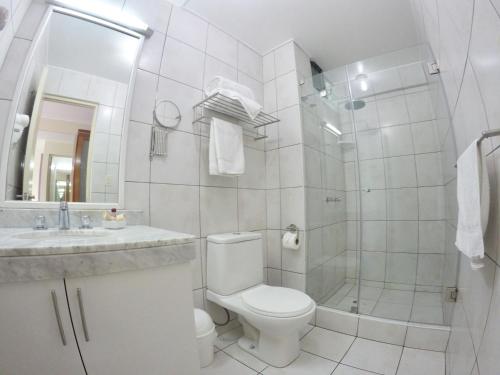 a white toilet sitting next to a shower in a bathroom at Hotel Runcu Miraflores in Lima