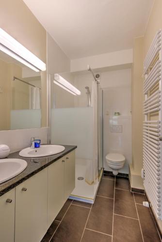 a bathroom with two sinks and a toilet at Res. Golf Zoute in Knokke-Heist