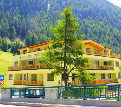 a large building with a tree in front of it at A Casa Residenz in Sölden