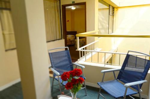 two blue chairs and a vase with red flowers on a balcony at Hotel Bonaventure in Quito