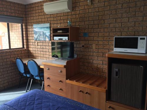 a kitchen with a microwave and a bed at Whale Fisher Motel in Eden