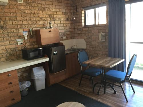 a small kitchen with a table and a sink and a table and chairs at Whale Fisher Motel in Eden