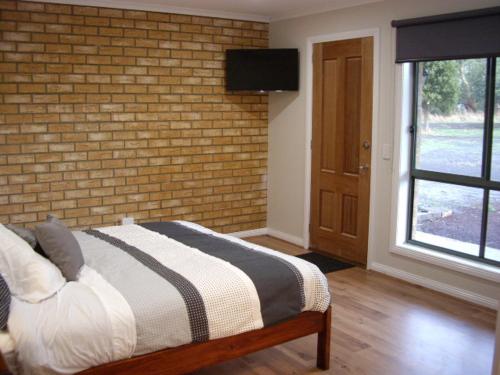 a bedroom with a bed and a brick wall at Ruby Rose in Simpson