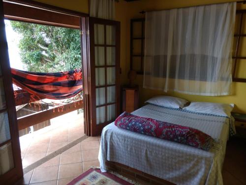 1 dormitorio con 1 cama y puerta corredera de cristal en Pousada Tony Montana en Praia de Araçatiba