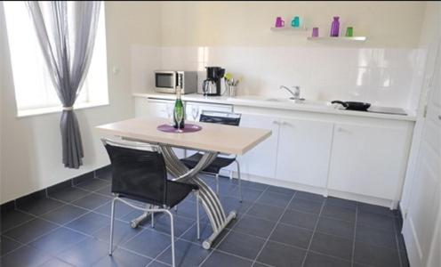 a kitchen with a table and two chairs and a sink at Aux Jardins de L'Isle in Vienne