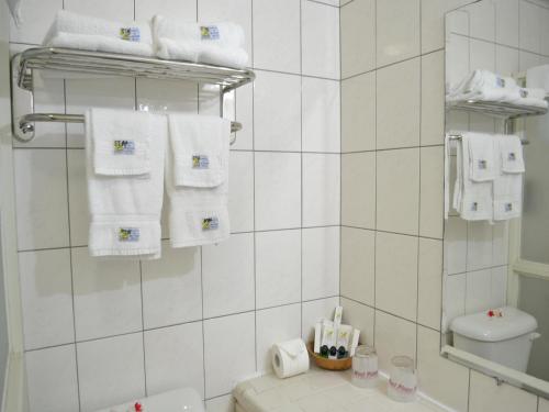 La salle de bains blanche est pourvue de serviettes blanches et de toilettes. dans l'établissement West Plaza Downtown, à Koror