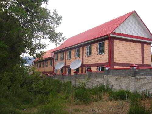 a large brick building with a red roof at Mini-pansionat Maksat in Cholpon-Ata