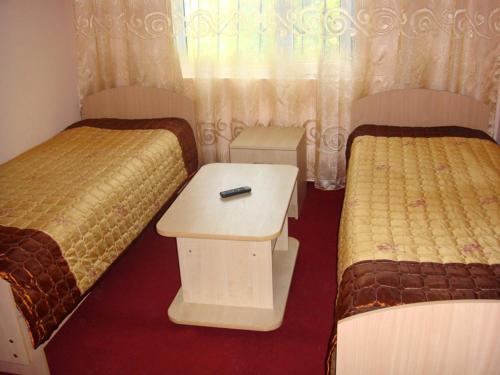 a room with two beds and a table between them at Mini-pansionat Maksat in Cholpon-Ata