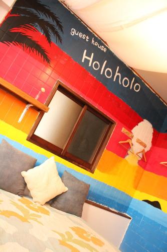 a bedroom with a colorful wall with a hotel sign at guest house Holoholo Ishigakijima in Ishigaki Island