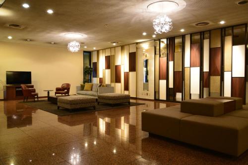 a lobby with couches and chairs and a television at Hotel Sunroute Sano in Sano