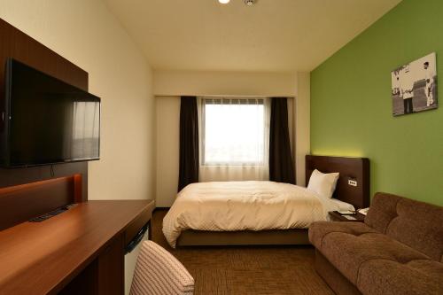 a hotel room with a bed and a couch at Hotel Sunroute Sano in Sano
