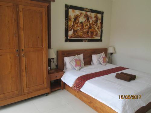 a bedroom with a bed and a painting on the wall at Amed Sunset Beach in Amed