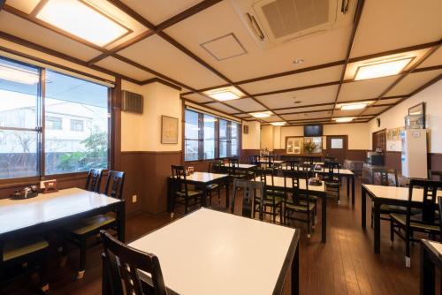 a dining room with tables and chairs and windows at Towada City Hotel in Towada