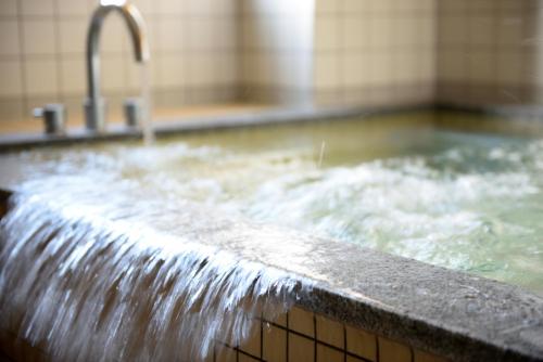 a bath tub with water pouring out of a faucet at Towada City Hotel in Towada