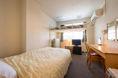 a bedroom with a bed and a desk and a computer at Towada City Hotel in Towada
