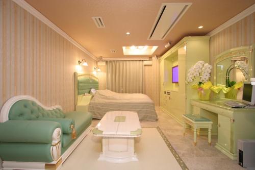 a bedroom with a bed and a couch and a table at Hotel AtoZ Saku (Adult Only) in Saku