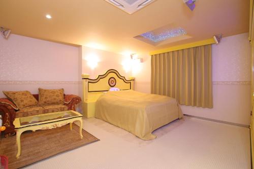 a bedroom with a bed and a couch and a chair at Hotel AtoZ Saku (Adult Only) in Saku