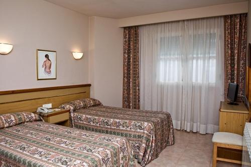 a hotel room with two beds and a television at Hotel La Piqueta in Benasal