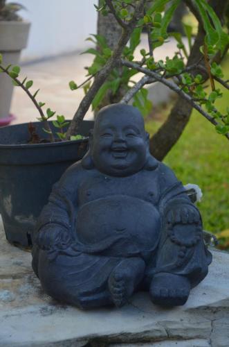 a statue of a monk sitting next to a plant at La Maison Du Voyage in Tevaitoa