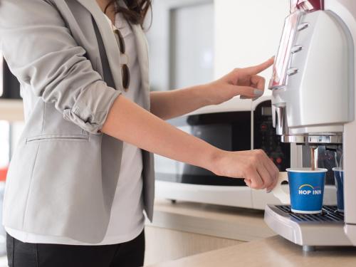 a woman is using a coffee machine at HOP INN Lampang City Center in Lampang