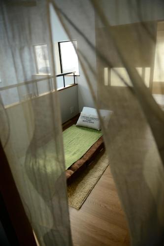 a small room with a bed with a green rug at Nanni Saiin Machiya in Kyoto