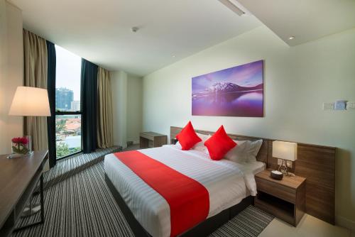 Cette chambre comprend un grand lit avec des oreillers rouges. dans l'établissement Riccarton Capsule Hotel, à Kuala Lumpur