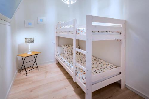 a white bunk bed in a room with a table at Can Mero in Malgrat de Mar