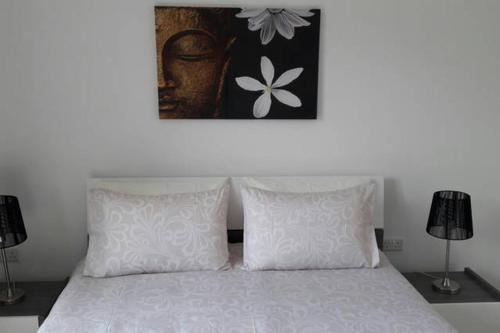 a bed with two pillows and a picture above it at Blue Skies Penthouse in Marsaskala