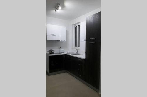 a kitchen with a black cabinet and a sink at Blue Skies Penthouse in Marsaskala