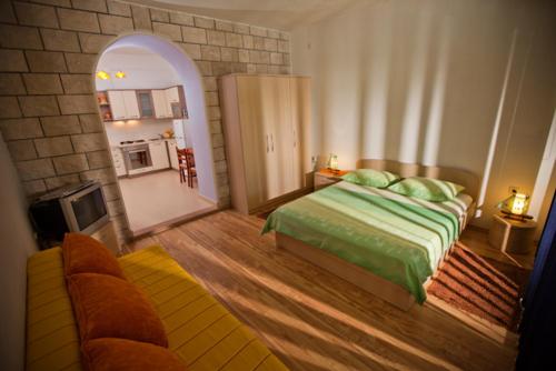 a bedroom with a bed and a couch and a mirror at Apartmani Denis Vela in Podgora