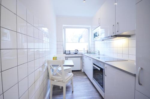 a white kitchen with a chair and a table at Ostseehaus Dreesen in Timmendorfer Strand