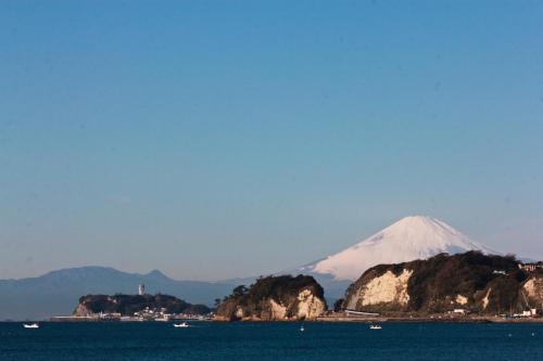 a mountain in the background with a body of water at Guest House Kamejikan -turtle time- in Kamakura