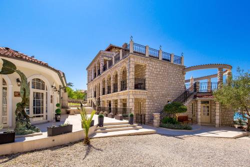Un grand bâtiment en briques avec un escalier se trouve devant. dans l'établissement Villas Arbia - Margita Beach hotel, à Rab