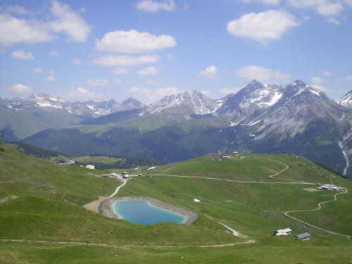 a view of a mountain range with a blue lake at Hof Arosa in Arosa