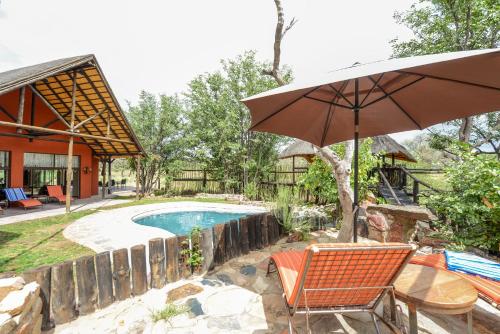 an umbrella and chairs next to a swimming pool at Hobatere lodge in Otjovasandu
