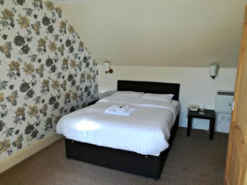 a bedroom with a white bed with flowers on the wall at The Lodge On The Loch Onich in Onich