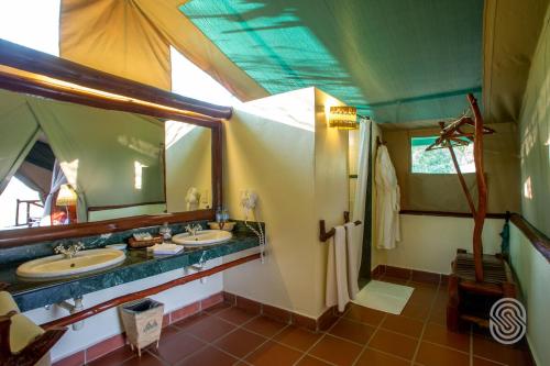 Baño con 2 lavabos y espejo en Mbuzi Mawe Serena Camp, en Serengeti