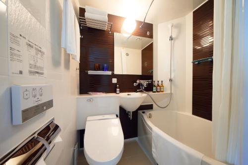 a bathroom with a toilet and a sink and a tub at Kyoto Tower Hotel Annex in Kyoto