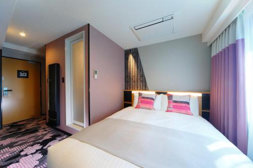 a bedroom with a large white bed with pink pillows at Kyoto Tower Hotel Annex in Kyoto