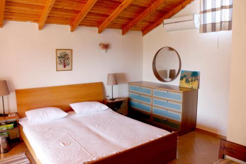 sypialnia z łóżkiem, komodą i lustrem w obiekcie Agios Mamas Resort w mieście Nea Potidaea