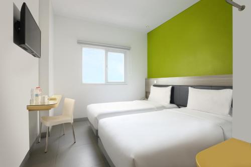 two beds in a hotel room with a green wall at Amaris Hotel Margorejo Surabaya in Surabaya