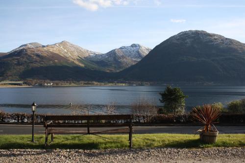 a bench on a hill overlooking a lake at Creag Mhor Lodge in Onich