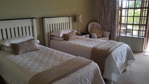 a bedroom with two beds and a chair at Olive Hill Country Lodge in Bloemfontein