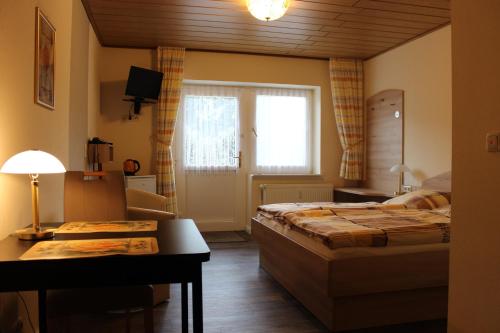 a bedroom with two beds and a table and a window at Pension Jahnkes Gasthaus in Todesfelde
