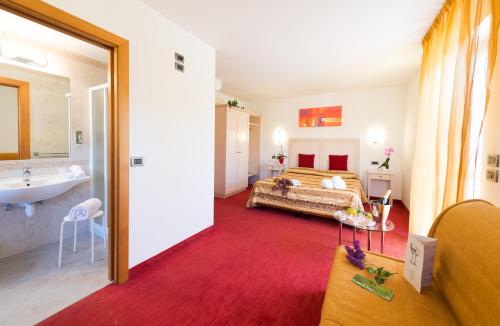 ein Schlafzimmer mit einem Bett und ein Badezimmer mit einem Waschbecken in der Unterkunft Nature Bio Hotel Elite in Levico Terme
