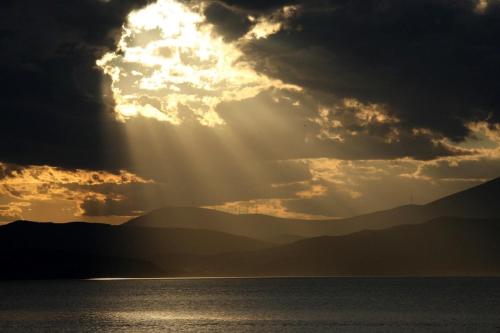 a sun shining through the clouds over a body of water at Villa Ostria in Vlikhós