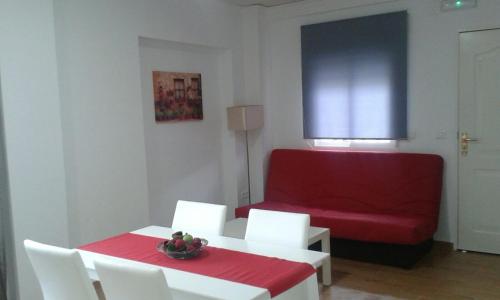 ネルハにあるApartamentos Tursolのリビングルーム(赤いソファ、テーブル、椅子付)
