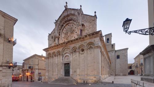 un gran edificio de piedra con un reloj. en Svegliarsi nei Borghi - La Patronale, en Troia