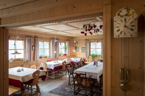 a dining room with tables and chairs and a clock at Charmehotel Uhrerhof - Deur in Ortisei