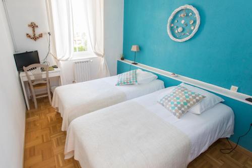 two beds in a room with a blue wall at Auberge de la Cauquiere in Le Beausset